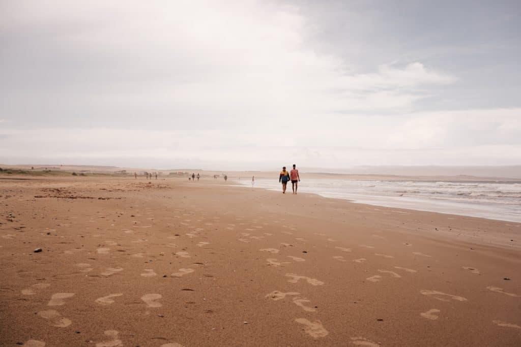 two men stroll on the beach