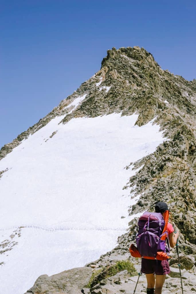 Female hiker looks into snow covered mountain path