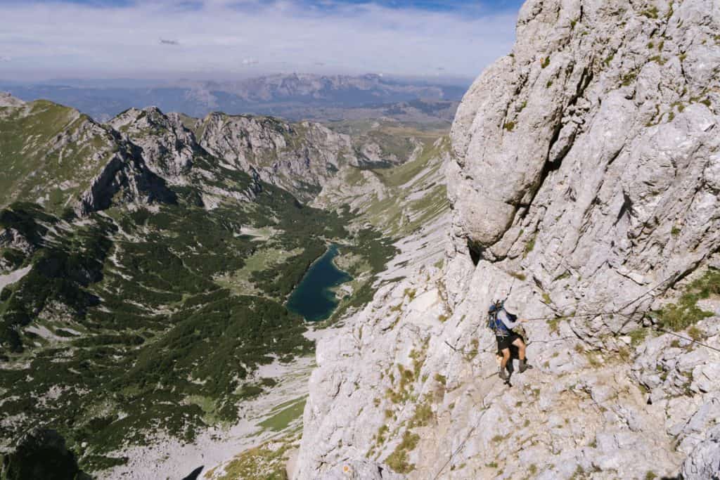 Man ascends the vertical face of Bobotov Kuk by using a cable