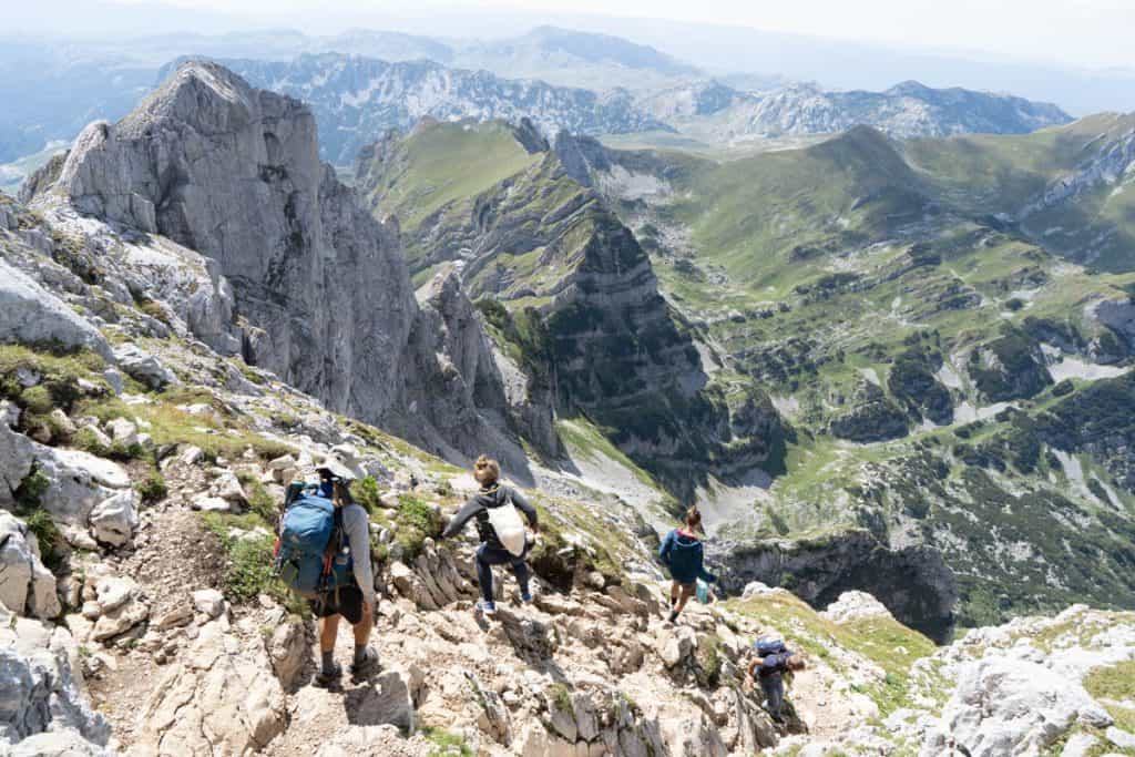 Group of people walk down steep path from Bobotov Kuk