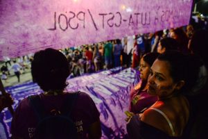 Protestor looks into crowd with a banner protesting Brazil's abortion bill
