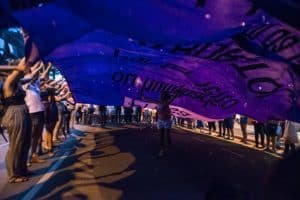 A child runs underneath a billowing protest banner with her arms outstretched