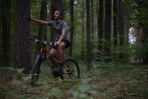 Man resting on bike in woods