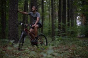 Man resting on bike in woods