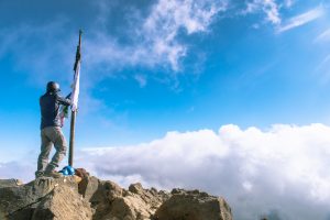 Man adjusts flags on the summit pole Nevado de Colima