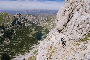 Man ascends the vertical face of Bobotov Kuk by using a cable