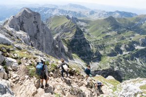 Group of people walk down steep path from Bobotov Kuk