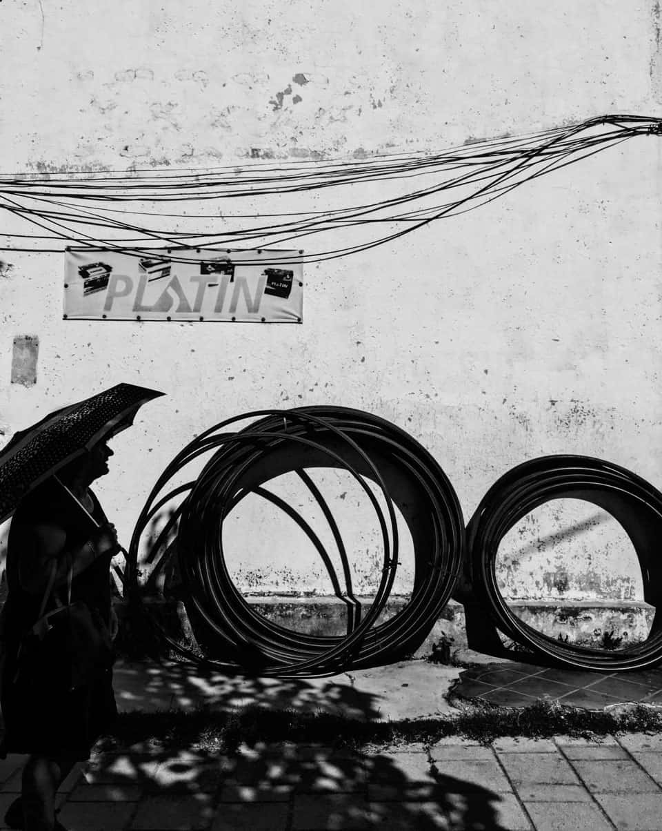 Silhouette of woman walking with huge circular bundles of wires in backdrop