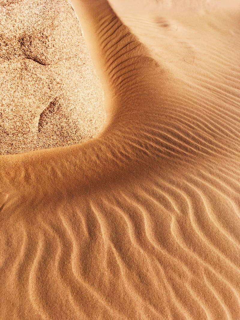 Pattern of sand dunes radiating out from a rock