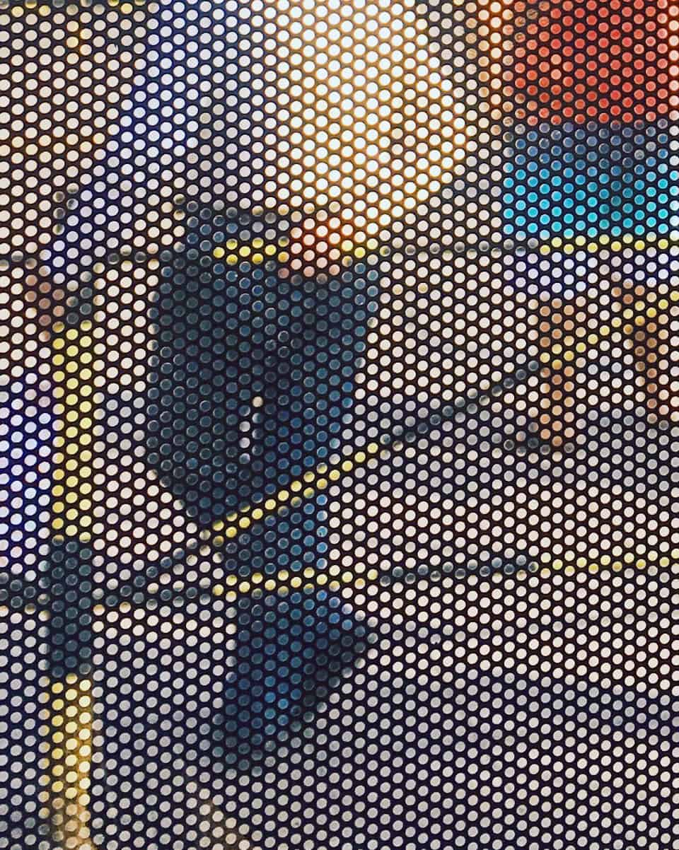 Dotted pixels construct an image of a pan standing against a fence