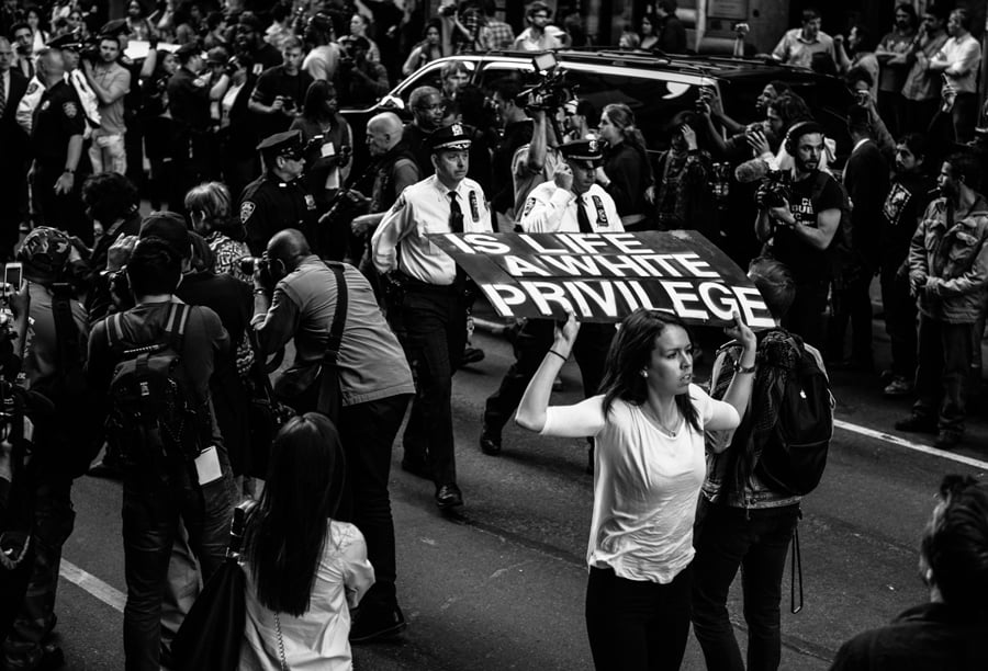 White woman carries a sign that reads 