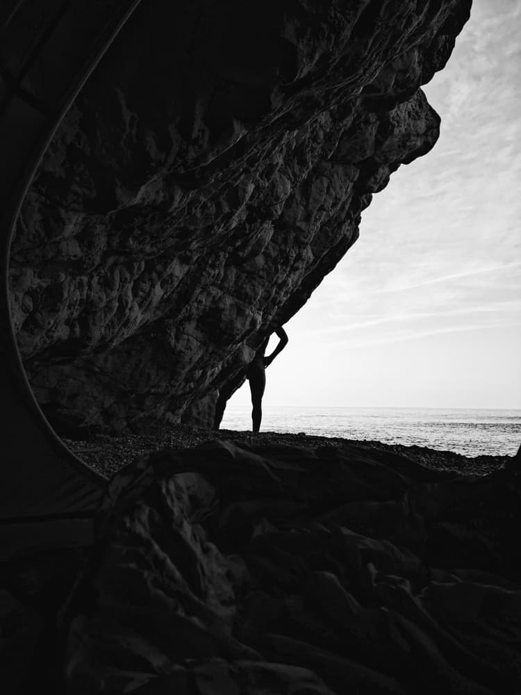 silhouette of a man against the rocky walls of gjipe beach with the sea in the background