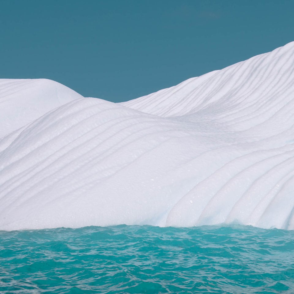 Elegant curve of a iceberg against the light blue water