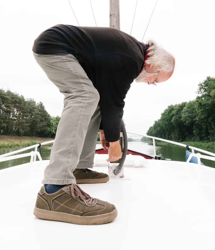 Upwards shot of a man on the deck of his boat adjusting a part