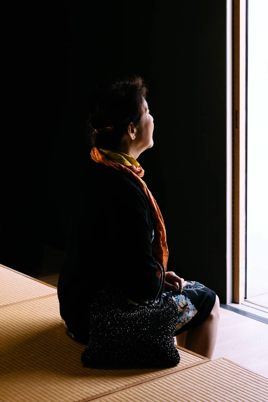 Seated woman serenely looks into the light of an open doorway